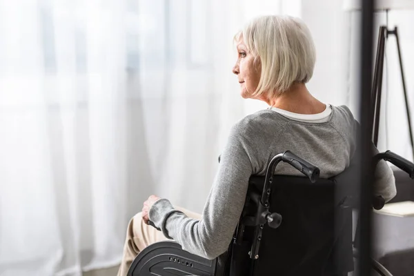 Pensive disabled senior woman sitting on wheelchair and looking away — Stock Photo