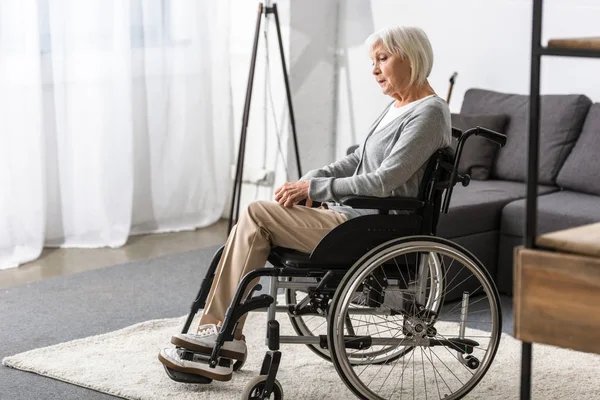 Жінка з обмеженими можливостями сидить у інвалідному візку і дивиться вниз — стокове фото