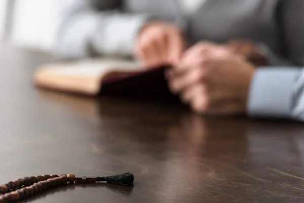 Selective focus of two people and wooden rosary on foreground — Stock Photo