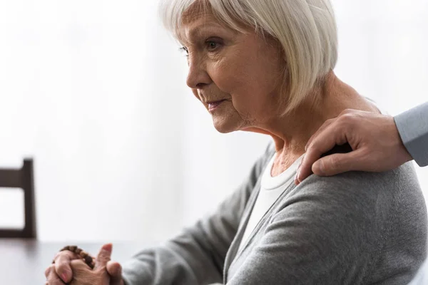 Partial view of man supporting senior mother with grey hair — Stock Photo