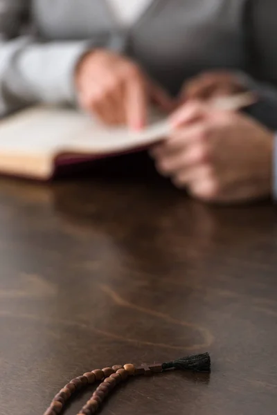 Selective focus of two people and wooden rosary on foreground — Stock Photo