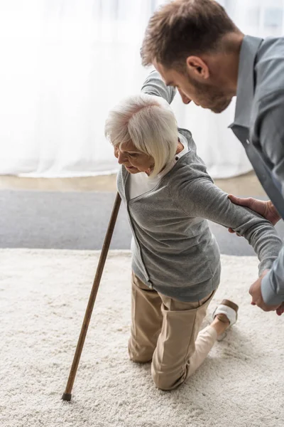Cropped view of man helping sick senior mother with cane — Stock Photo