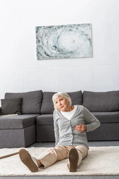 Souffrance femme âgée avec crise cardiaque assis sur le tapis — Photo de stock