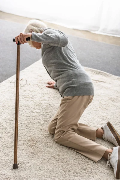 Kranke Seniorin mit Holzstock auf Teppich gefallen — Stockfoto
