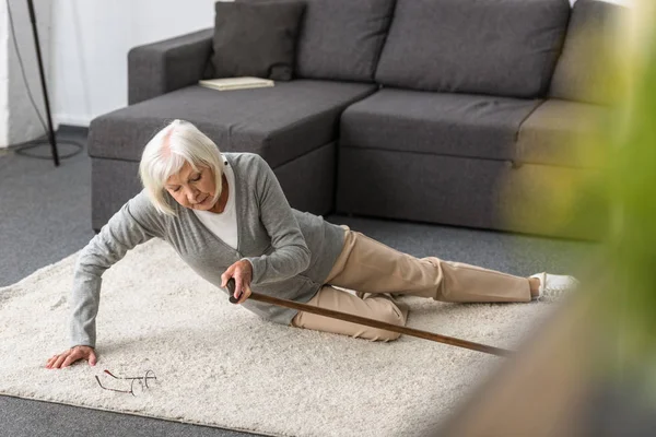 Suffering senior woman with heart attack on carpet — Stock Photo