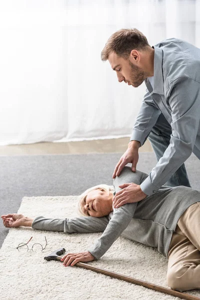 Adult man with sick senior mother lying on carpet — Stock Photo