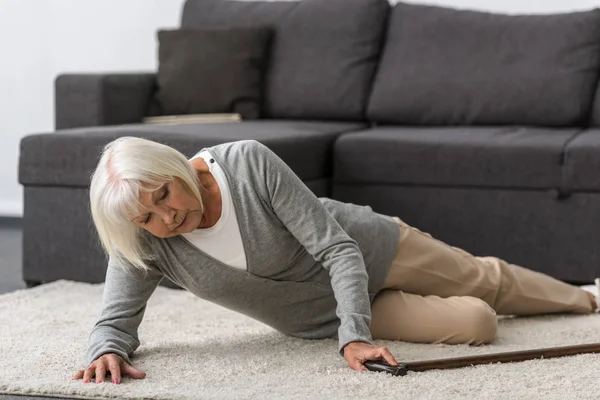 Kranke Seniorin mit Stock auf Teppich liegend — Stockfoto