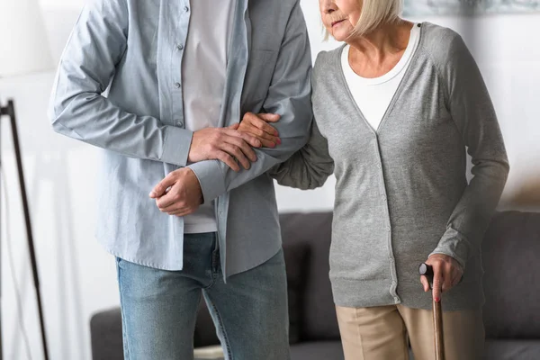 Mann hilft Seniorin zu Hause mit Rohrstock — Stockfoto