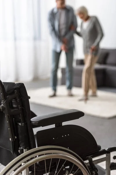 Selektiver Fokus des erwachsenen Sohnes und der Mutter im Rollstuhl im Vordergrund — Stockfoto