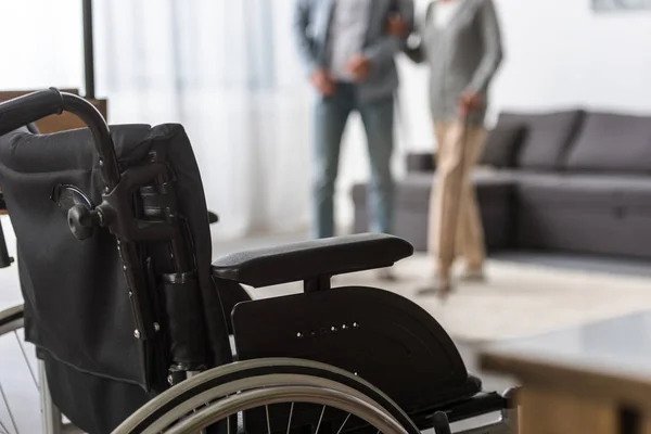 Вибірковий фокус дорослого сина і старшої матері з інвалідним візком на передньому плані — стокове фото