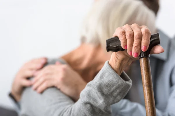 Selective focus of man embracing senior mother with cane — Stock Photo