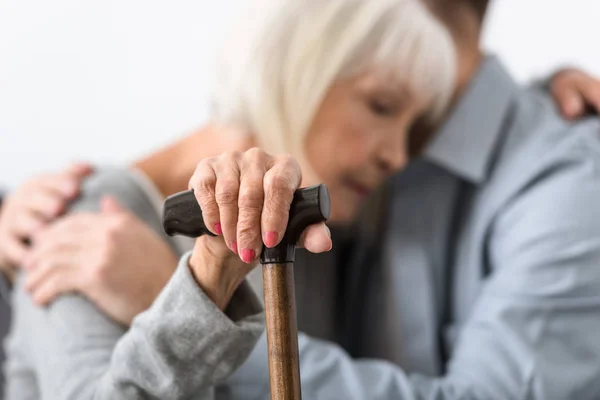 Selective focus of man embracing senior mother with cane — Stock Photo