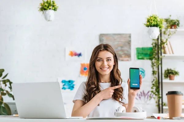 KYIV, UKRAINE - 17 de abril de 2019: Menina atraente apontando com o dedo para o smartphone com o aplicativo Twitter na tela . — Fotografia de Stock