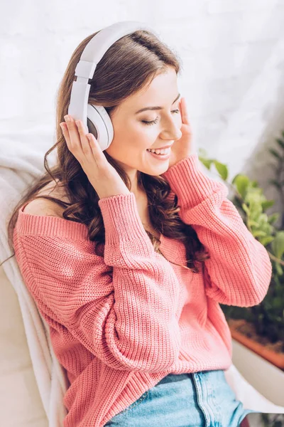 Красива дівчина посміхається і слухає музику в навушниках із закритими очима — стокове фото