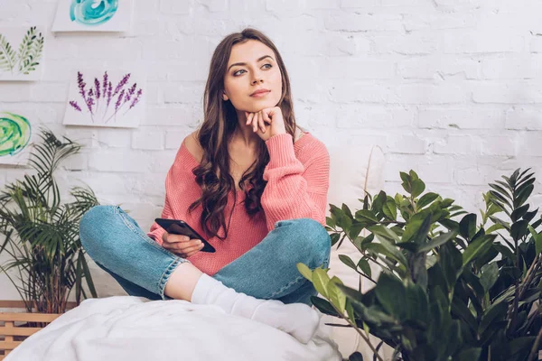 Chica bastante soñadora mirando hacia otro lado mientras está sentado con las piernas cruzadas - foto de stock