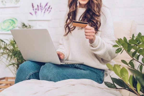 Vista parziale di giovane donna che utilizza il computer portatile e in possesso di carta di credito — Foto stock