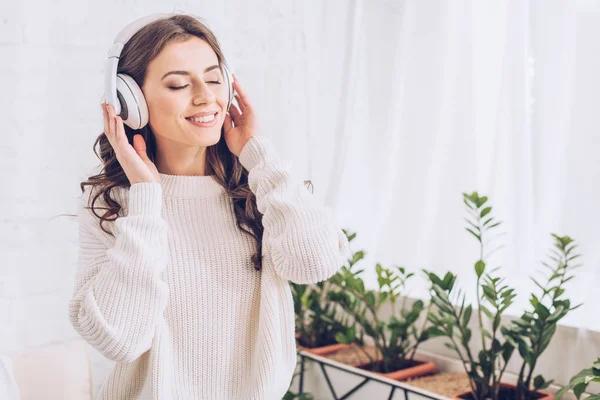 Щаслива молода жінка слухає музику в навушниках із закритими очима — стокове фото