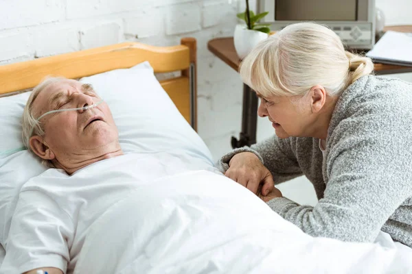 Sad senior woman with husband in coma in hospital — Stock Photo