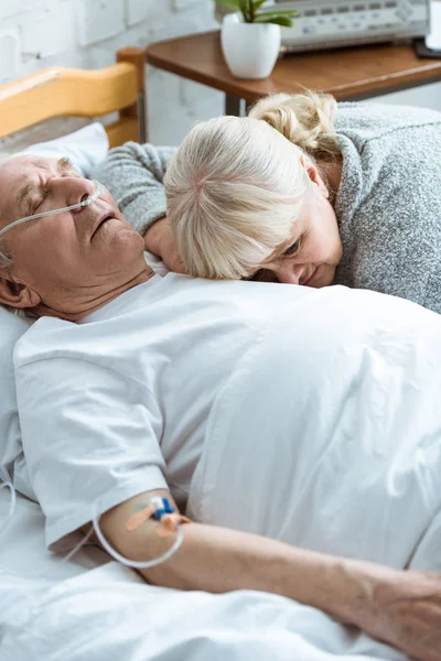 Sad senior woman with husband in coma in clinic — Stock Photo