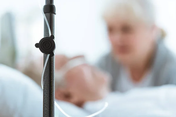 Selective focus of sad senior woman with husband in coma in clinic — Stock Photo