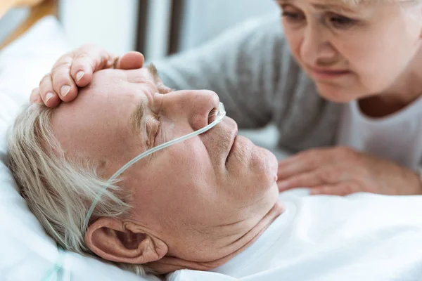 Обрезанный вид пожилой женщины с мужем в коме в больнице — стоковое фото