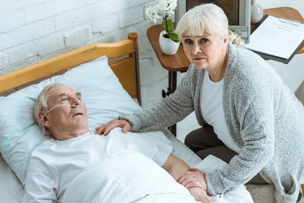 Над головой вид грустной пожилой женщины и мужчины в коме в больнице — стоковое фото