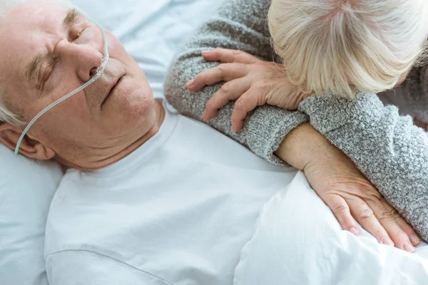 Обрезанный вид бессознательного пожилого мужчины и грустной жены в клинике — стоковое фото