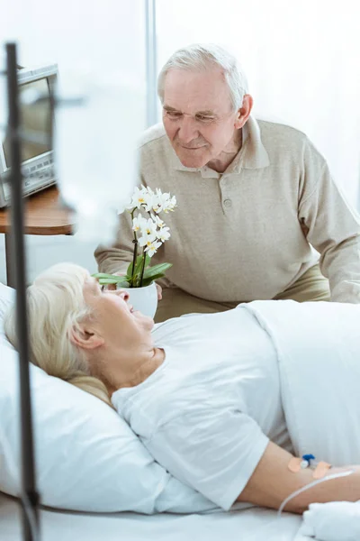 Улыбающаяся больная пожилая женщина смотрит на мужа в клинике — стоковое фото