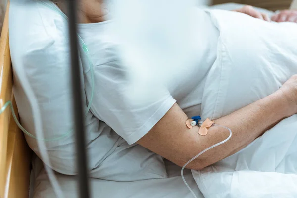 Vista parziale della donna malata sdraiata sul letto durante la terapia endovenosa in clinica — Foto stock