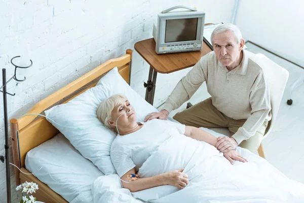 Overhead view of sick senior woman with husband in clinic — Stock Photo