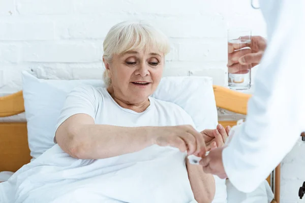 Partial view of doctor giving medicine and glass of water to patient — Stock Photo