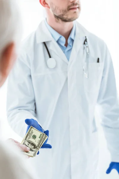 Vue partielle de l'homme âgé donnant pot de vin au médecin sur blanc — Photo de stock