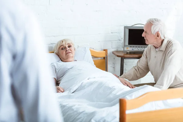 Vue partielle du médecin en manteau blanc, malade et aîné à l'hôpital — Photo de stock