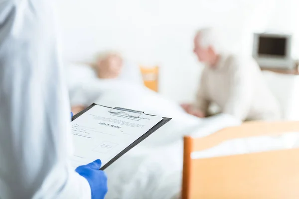 Vista parcial del médico portapapeles, paciente enfermo y hombre mayor en la clínica - foto de stock