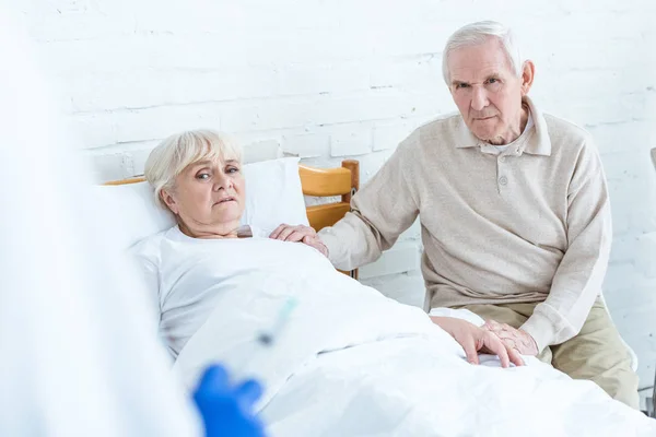 Worried ill senior woman and her husband in hospital — Stock Photo