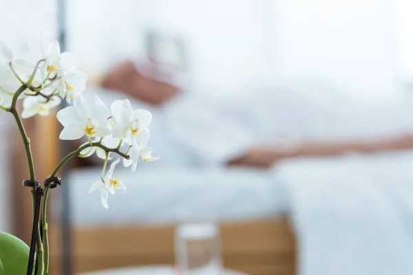 Foco seletivo do paciente doente na clínica e orquídeas em primeiro plano — Fotografia de Stock
