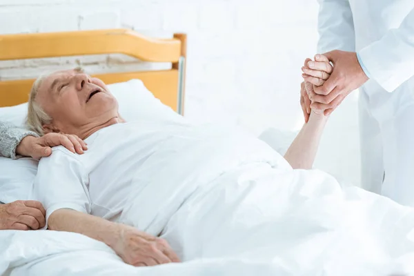 Partial view of doctor standing near patient and checking pulse — Stock Photo