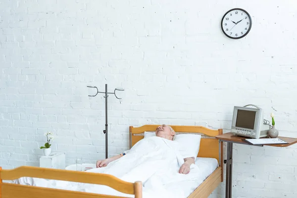 Paciente mayor acostado en la cama en la sala de hospital - foto de stock