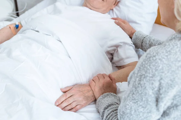 Partial view of senior woman with ill husbend in clinic — Stock Photo