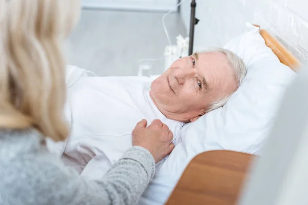 Частковий погляд на старшу жінку і усміхненого хворого чоловіка в клініці — стокове фото
