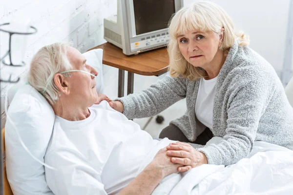 Triste femme âgée avec mari malade à l'hôpital — Photo de stock
