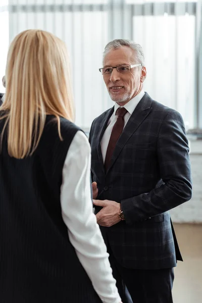 Back view of blonde businesswoman standing near businessman in glasses — Stock Photo