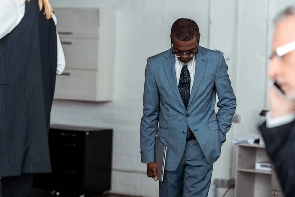 Foyer sélectif de l'homme d'affaires afro-américain tenant ordinateur portable près des partenaires — Photo de stock