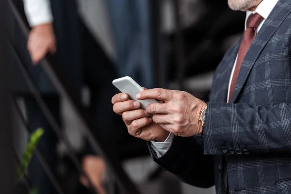 Vista ritagliata di uomo d'affari utilizzando smartphone in ufficio — Foto stock