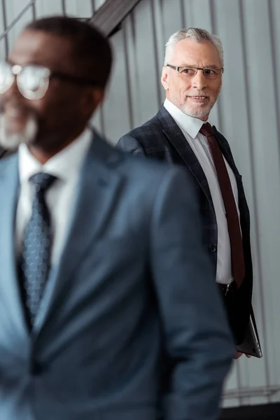 Selective focus of businessman in glasses looking at african american man — Stock Photo