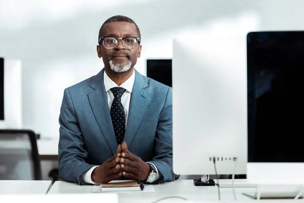 Успешный африканский американский бизнесмен с сжатыми руками в офисе — стоковое фото