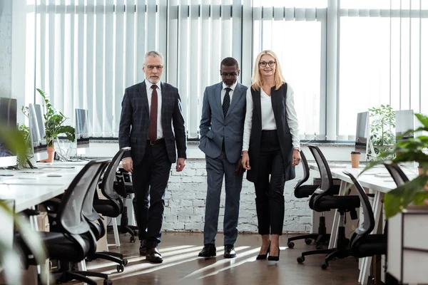 Selective focus of african american businessman walking near partners in office — Stock Photo