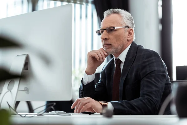 Enfoque selectivo de hombre de negocios en gafas mirando monitor de ordenador - foto de stock