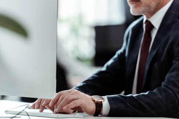 Vista recortada del hombre de negocios escribiendo en el teclado de la computadora en la oficina - foto de stock