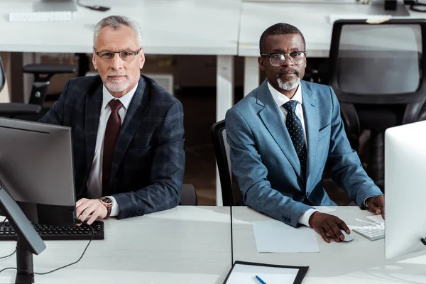 Handsome african american businessman near coworker in office — Stock Photo
